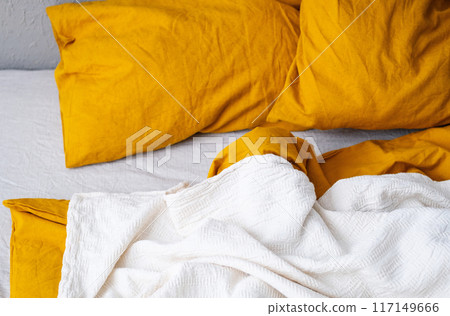 Cozy bed with yellow pillows and white blanket in modern bedroom. Cozy bed with yellow pillows and white blanket in modern bedroom. 117149666