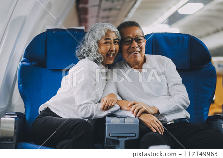 .A mature couple enjoys a plane ride sitting near the window. They looked out into the sky. Immerse yourself in the scenery and excitement of the journey. To create precious memories together 117149963
