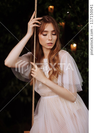 Elegant woman on wooden swing. 117150041