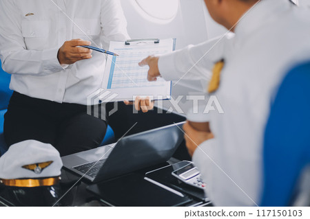 Professional pilot woman in uniform has teamwork meeting for success flight in aviation business. Young female captain instructor sitting in office and working or training commercial airline crew. Professional pilot woman in uniform has teamwork meeting for success flight in aviation business. Young female captain instructor sitting in office and working or training commercial airline crew. 117150103