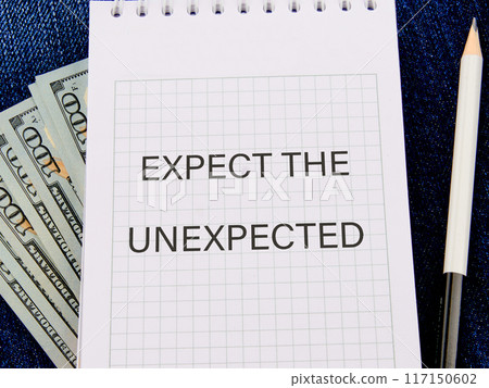 Text expect the unexpected in a notebook in a composition with American hundred dollar bills and a pencil Text expect the unexpected in a notebook in a composition with American hundred dollar bills and a pencil 117150602