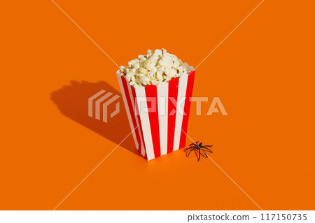 Striped box with popcorn and spider on an orange background. Halloween celebration concept. 117150735