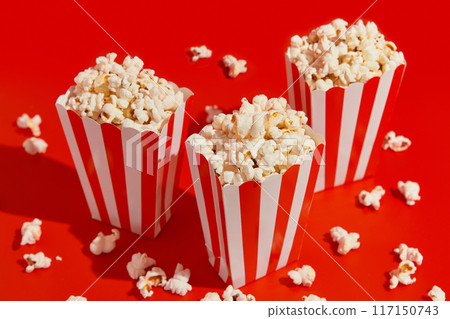 Striped boxes with popcorn on a red background 117150743