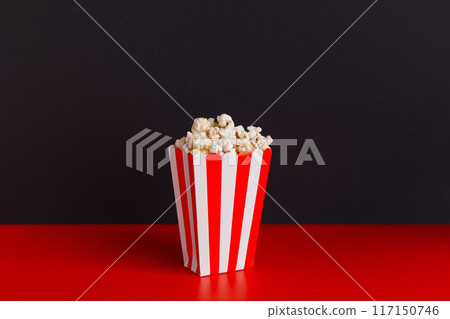 Striped box with popcorn on a red and black background Striped box with popcorn on a red and black background 117150746