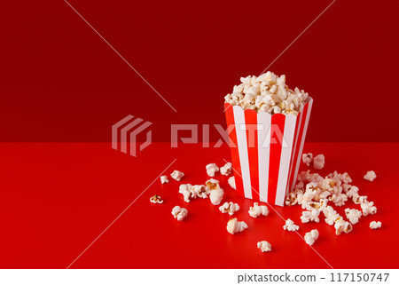Striped box with popcorn on a red background 117150747
