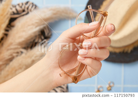 Beautiful womans hands with nude nail design on blue background. Manicure, pedicure beauty salon concept 117150793