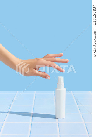Womans hand holding white tube on blue tile background. Beauty treatment. Skin care routine Womans hand holding white tube on blue tile background. Beauty treatment. Skin care routine 117150834