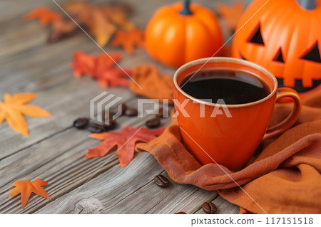 Warm coffee in an orange mug, perfectly blending with the autumn leaves on a wooden table 117151518
