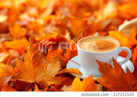 Cozy autumn cappuccino in a white cup nestled among vibrant orange leaves, perfect for fall mornings 117151520