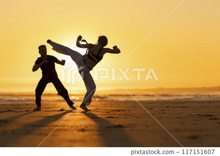 A man and a woman are practicing martial arts on a beach 117151607