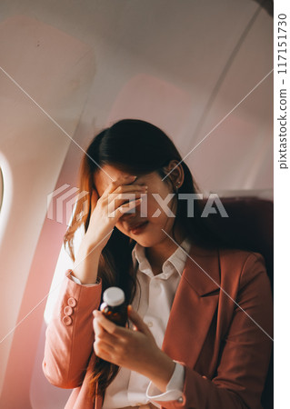 Tired asian woman with headache feeling sick while sitting in the airplane , Passengers near the window. 117151730