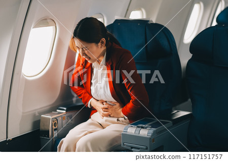 Photo of a frustrated woman sitting on an airplane with her head in her hands. Asian woman sitting in a seat in airplane 117151757