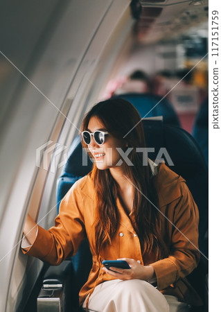 Joyful asian woman sits in the airplane and using tablet while go to travel 117151759
