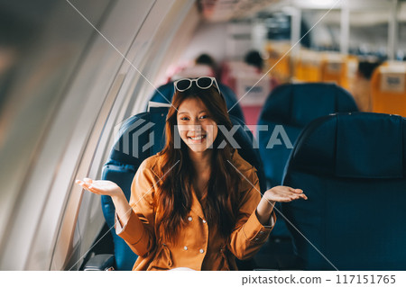 Joyful asian woman sits in the airplane and using tablet while go to travel 117151765