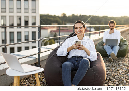 Remote work on rooftop terrace with laptops and mobile devices 117152122