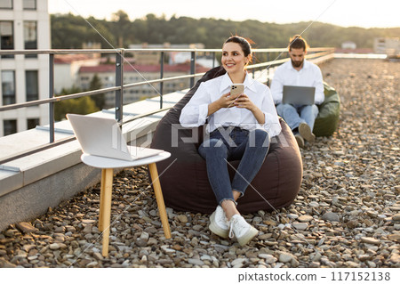 People working outdoors with laptops on rooftop terrace People working outdoors with laptops on rooftop terrace 117152138