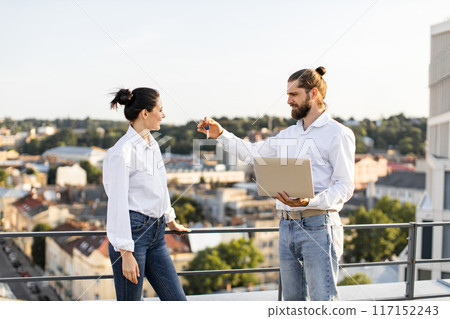 Couple discussing new house keys on city rooftop Couple discussing new house keys on city rooftop 117152243