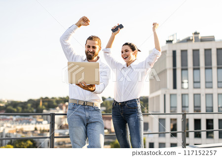 Happy business colleagues celebrating success on rooftop 117152257