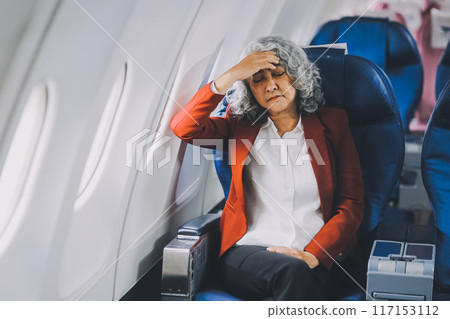 Mature with headache with nausea feeling sick while sitting in the airplane , Passengers near the window. 117153112