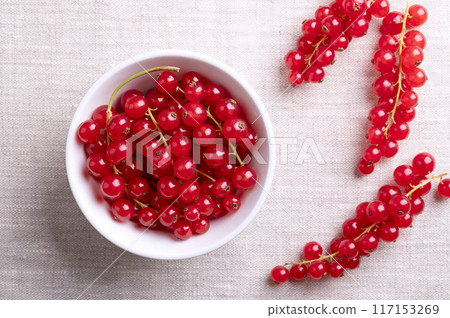 Red currant berries, fresh ripe and raw redcurrants in a white bowl on linen fabric. Ready to eat spherical edible fruits of Ribes rubrum, sweet fruits with an intense red color. Close-up food photo. Red currant berries, fresh ripe and raw redcurrants in a white bowl on linen fabric. Ready to eat spherical edible fruits of Ribes rubrum, sweet fruits with an intense red color. Close-up food photo. 117153269