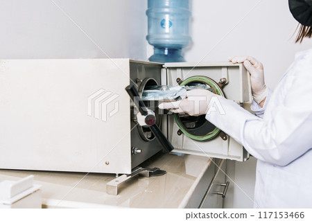 Dentist with dental sterilizer, Dentist hands sterilizing his tools, Dentist with dental autoclave, Close up of dentist with steam sterilizer. Hands with dental sterilizer machine Dentist with dental sterilizer, Dentist hands sterilizing his tools, Dentist with dental autoclave, Close up of dentist with steam sterilizer. Hands with dental sterilizer machine 117153466