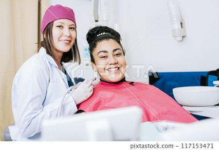 Portrait of smiling dentist with female patient in medical office, Female dentist with smiling female patient looking at camera, Professional dentist with female patient in office 117153471