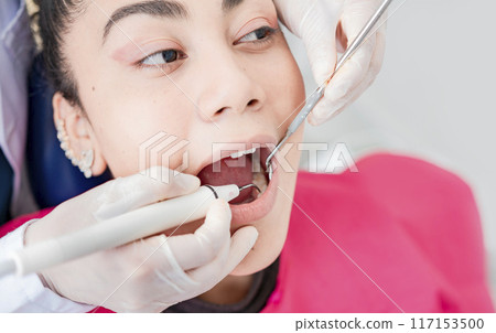 Close up of dentist checking patient with excavator and dental mirror, Dentist checking patient with excavator and dental mirror, Patient checked by dentist, Dentist doing dental checkup Close up of dentist checking patient with excavator and dental mirror, Dentist checking patient with excavator and dental mirror, Patient checked by dentist, Dentist doing dental checkup 117153500