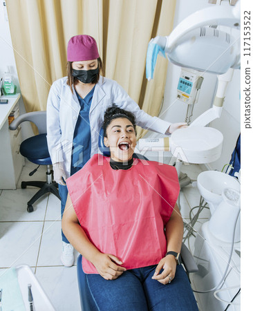 Dentist performing intraoral radiography assessment on a patient, a dentist performing dental x-rays in the office. Intraoral radiography concept, Dentist performing intraoral dental x-ray on a 117153522