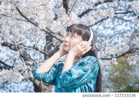 Woman listening to music among cherry blossoms 117153536