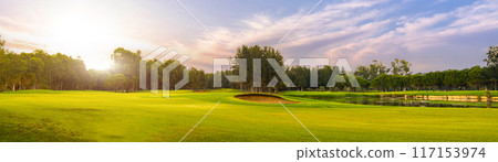 Golf course at sunset with beautiful sky. Picturesque panoramic view of golf fairway with bunker Golf course at sunset with beautiful sky. Picturesque panoramic view of golf fairway with bunker 117153974