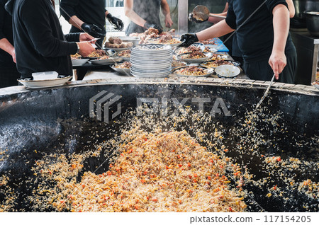 male chefs cook Uzbek pilaf with vegetables in a cauldron in restaurant. Traditional Asian Uzbek cuisine. Central Asian Pilaf Center Besh Qozon in Uzbekistan male chefs cook Uzbek pilaf with vegetables in a cauldron in restaurant. Traditional Asian Uzbek cuisine. Central Asian Pilaf Center Besh Qozon in Uzbekistan 117154205