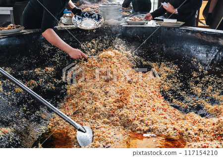 cooking traditional oriental Uzbek pilaf in huge cauldron in the kitchen at the Tashkent Pilaf Center Besh Qozon in Uzbekistan 117154210