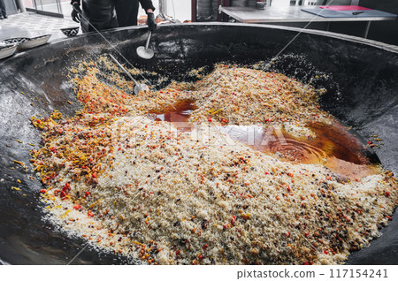 Uzbek rice pilaf with spices and vegetables in large cauldron in kitchen of a restaurant in Central Asian pilaf center in Tashkent in Uzbekistan close-up Uzbek rice pilaf with spices and vegetables in large cauldron in kitchen of a restaurant in Central Asian pilaf center in Tashkent in Uzbekistan close-up 117154241