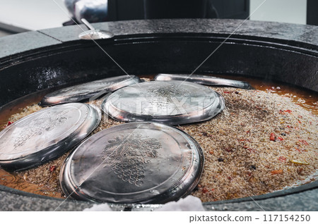 cooking traditional uzbek dish rice pilaf in a cauldron in kitchen of a restaurant in Central Asian pilaf center in Tashkent in Uzbekistan close-up 117154250