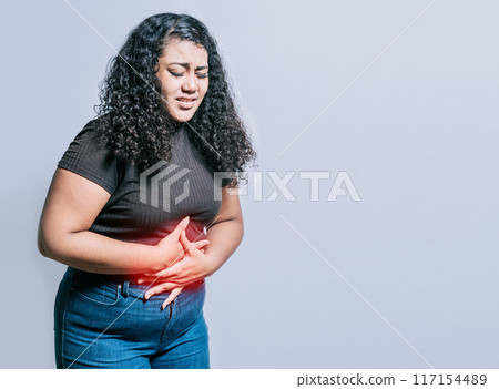 Woman with abdominal pain isolated. Young woman suffering stomach pain. Person with stomach pain isolated 117154489
