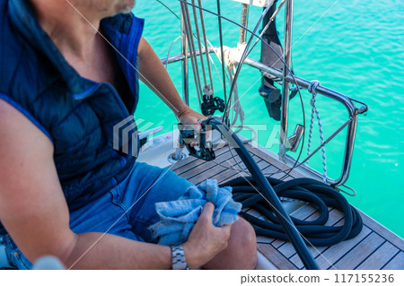 A man holds a petrole pistol and pours gasoline into a yacht on gas petrol station near sea for ship, boats and yachts in Rogoznica, Croatia. View from the yacht deck 117155236