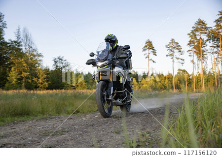 Driver riding motorcycle on empty road during sunset Driver riding motorcycle on empty road during sunset 117156120