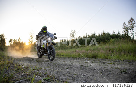 Driver riding motorcycle on empty road during sunset 117156128
