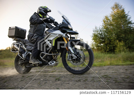 Driver riding motorcycle on empty road during sunset 117156129