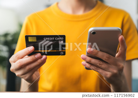 Woman hand holding credit card and using smartphone for paying products online via the Internet. Woman hand holding credit card and using smartphone for paying products online via the Internet. 117156902