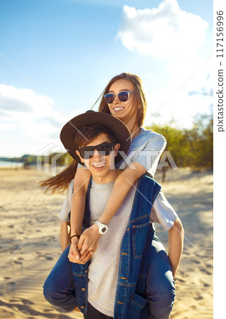 Group of friends enjoying time on beach. Laugh and smile. Friendly atmosphere. Guys enjoy photos. Group of friends enjoying time on beach. Laugh and smile. Friendly atmosphere. Guys enjoy photos. 117156996