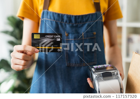 Shop owner hand holding credit card with card swipe machine for to pay. 117157320