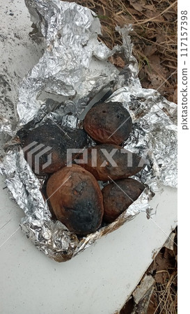 Blackened potatoes cooked on an open fire in foil with a crispy skin and soft insides 117157398