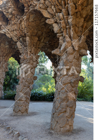 Stone colonnade resembling tree trunks by Antonio Gaudi in Park Guell, Barcelona. The arcade of stone columns 117157668