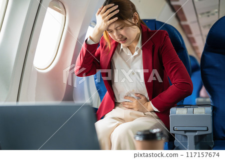 Tired asian businessman with headache with nausea feeling sick while sitting in the airplane, Passengers near the window. 117157674