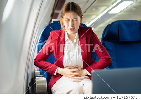 Tired asian businessman with headache with nausea feeling sick while sitting in the airplane, Passengers near the window. 117157675