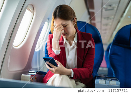 Tired businessman talking on the phone arguing work problems highlighting customer dissatisfaction while sitting in the airplane, Passengers near the window. Tired businessman talking on the phone arguing work problems highlighting customer dissatisfaction while sitting in the airplane, Passengers near the window. 117157711