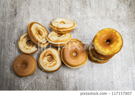 A stack of donuts with a variety of flavors and sizes A stack of donuts with a variety of flavors and sizes 117157807