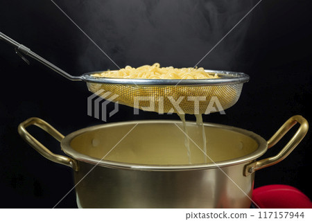 A pot of instant noodles is being drained through a strainer A pot of instant noodles is being drained through a strainer 117157944