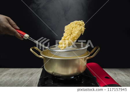 A pot of instant noodles is being drained through a strainer A pot of instant noodles is being drained through a strainer 117157945